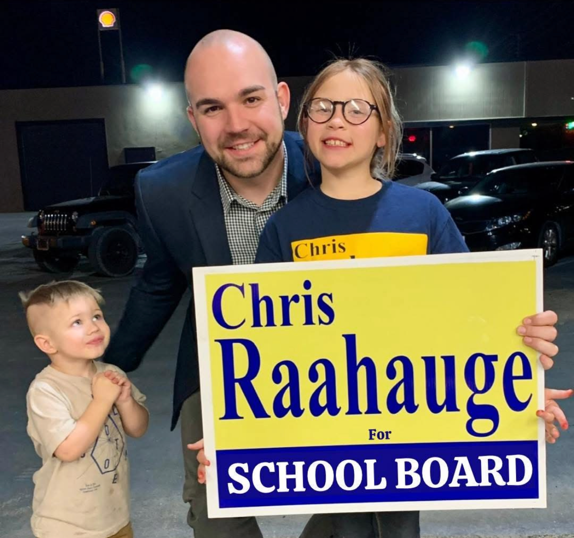 Chris with two children and a Chris Raahauge for School Board sign.