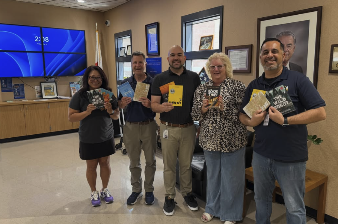 Chris and a group holding donated library books at Ramirez Intermediate School.